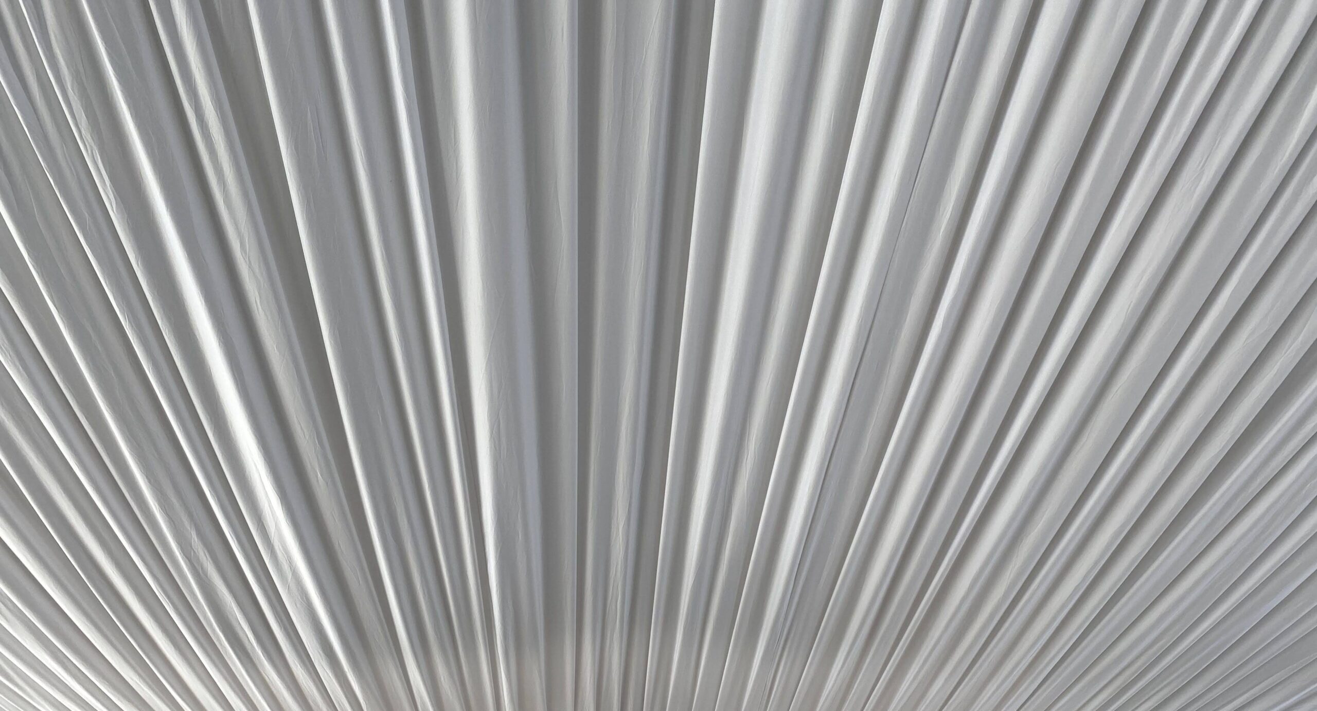 Close-up of white fabric pleats arranged in a fan-like pattern.